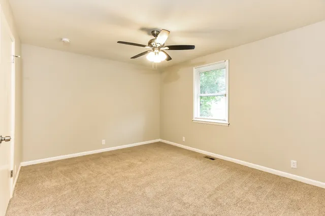 an empty room with windows and fan