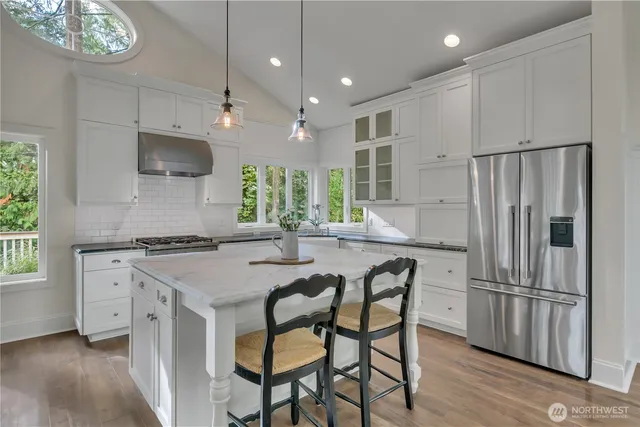 a kitchen with stainless steel appliances granite countertop a stove a refrigerator and a stove top oven