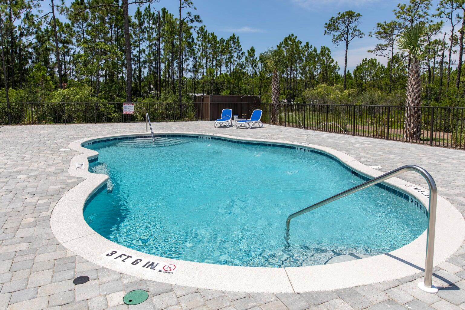 106 Heron's Crossing Santa Rosa Beach, FL 32459 - Photo 50 of 65 a view of a swimming pool with a yard and trees in the background