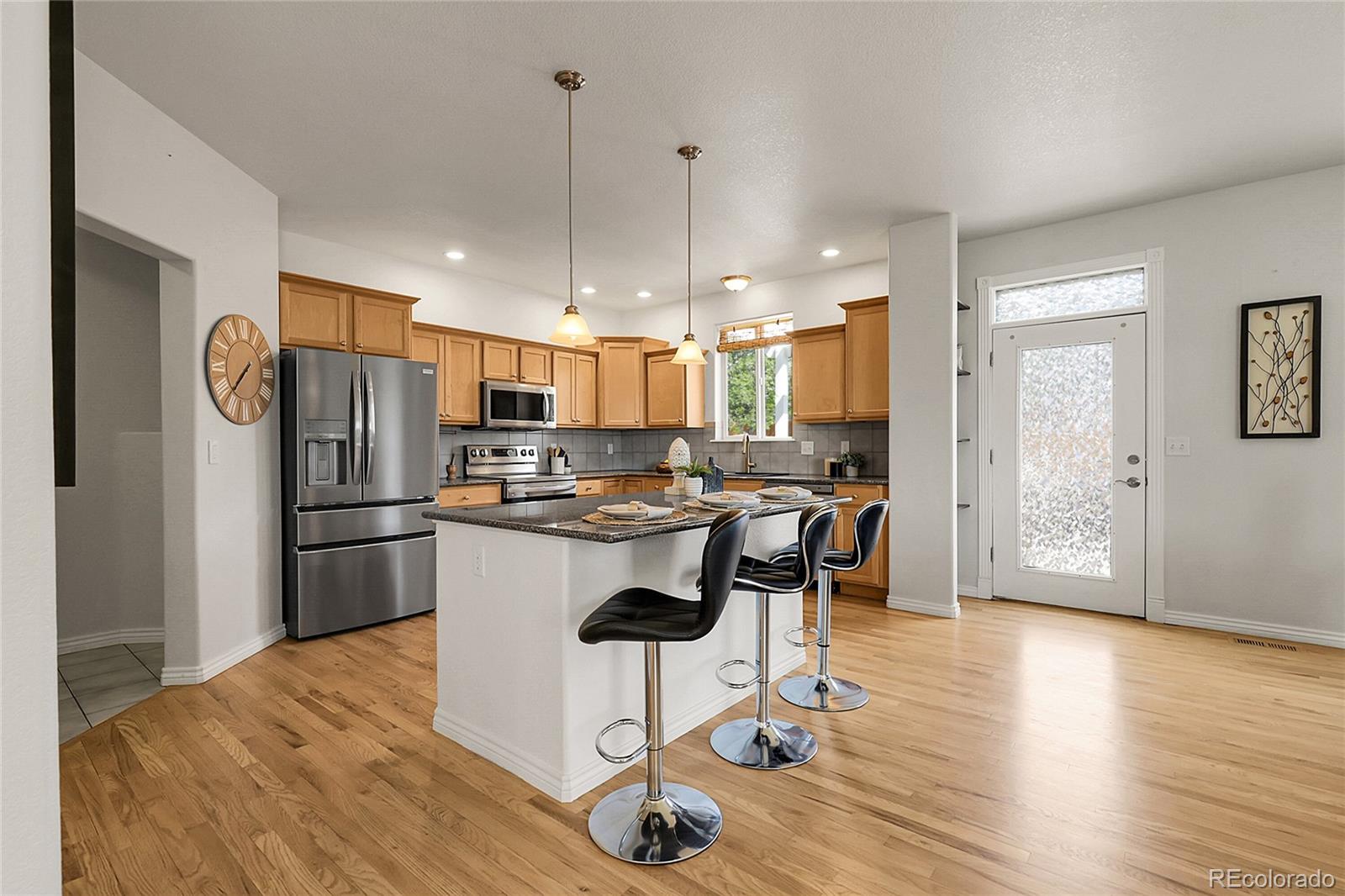 3406 Purcell Street Brighton, CO 80601 - Photo 16 of 50 a kitchen with stainless steel appliances granite countertop a refrigerator a stove a sink dishwasher and a dining table with wooden floor