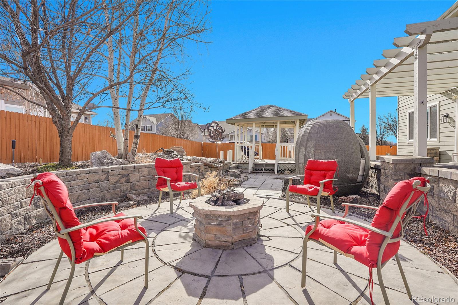 3406 Purcell Street Brighton, CO 80601 - Photo 41 of 50 a view of a patio with a dining table and chairs under an umbrella with large trees