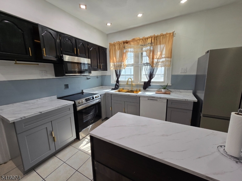 170 Spring Street Passaic, NJ 07055 - Photo 11 of 16 a kitchen with stainless steel appliances a stove refrigerator sink microwave and cabinets