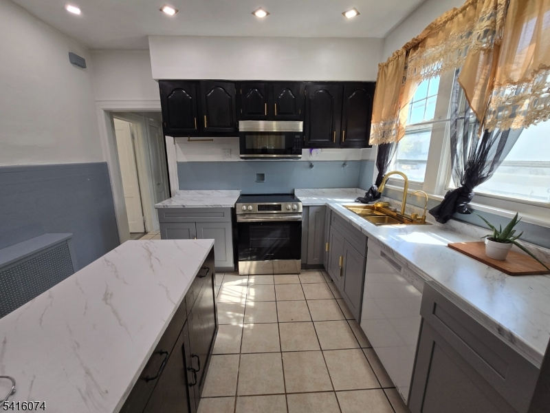 170 Spring Street Passaic, NJ 07055 - Photo 12 of 16 a kitchen with stainless steel appliances a stove a sink a microwave a refrigerator and cabinets
