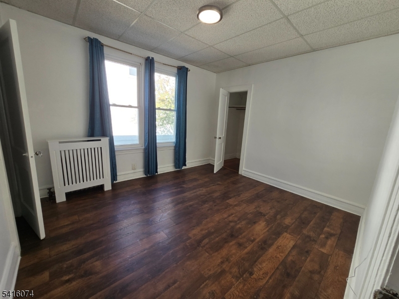 170 Spring Street Passaic, NJ 07055 - Photo 5 of 16 an empty room with wooden floor and windows