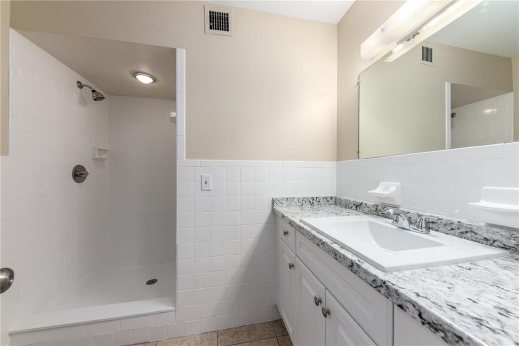 333 Southeast Martin Avenue, Unit 57 Stuart, FL 34996 - Photo 15 of 16 a bathroom with a granite countertop sink a mirror and shower