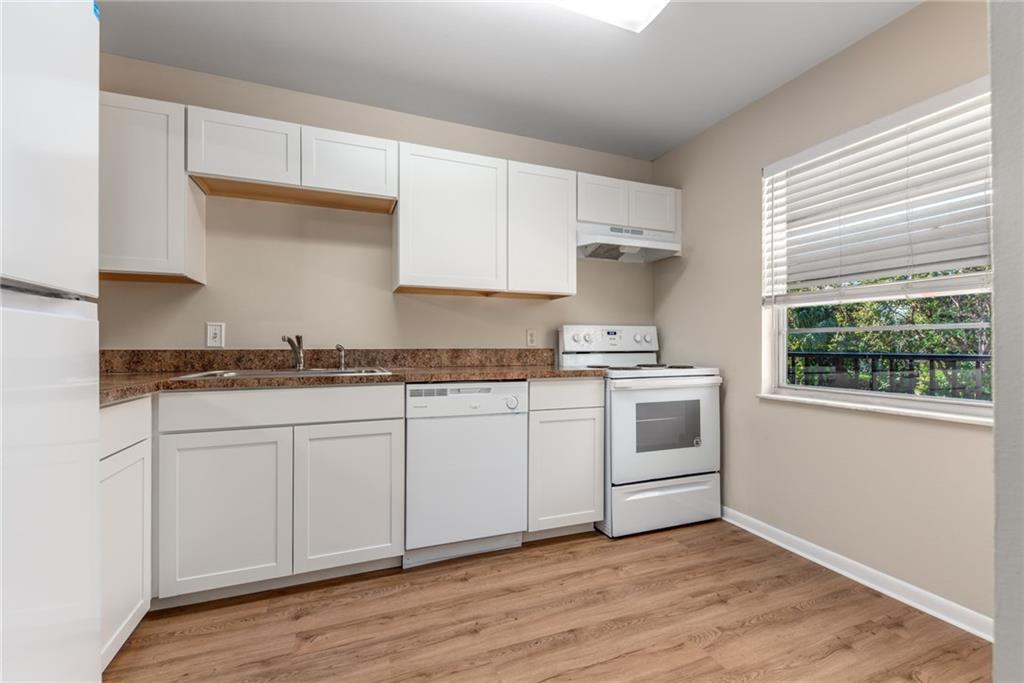 333 Southeast Martin Avenue, Unit 57 Stuart, FL 34996 - Photo 9 of 16 a kitchen with granite countertop white cabinets and white appliances