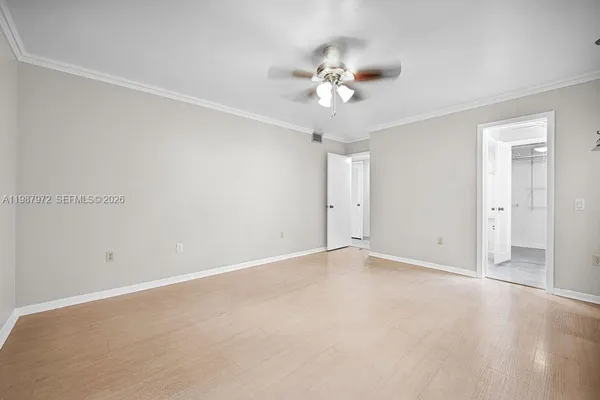 an empty room with a chandelier fan and closet area