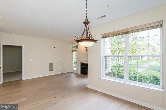 an empty room with windows a fireplace and wooden floor