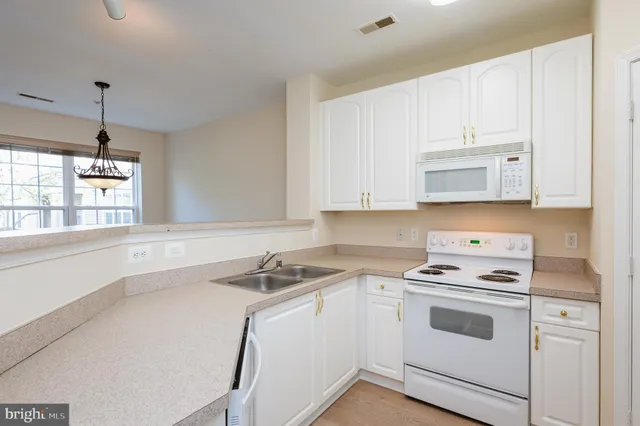 a white kitchen with sink a stove and refrigerator