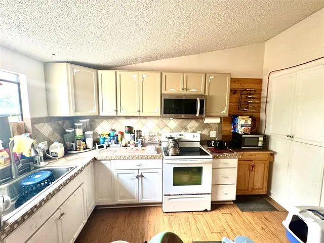 a kitchen with stainless steel appliances granite countertop a stove a sink dishwasher and a microwave with wooden floor
