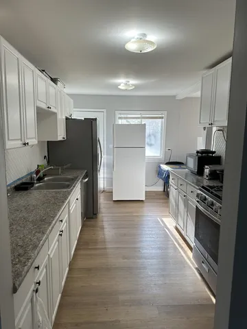 a large kitchen with stainless steel appliances granite countertop a stove refrigerator and a sink