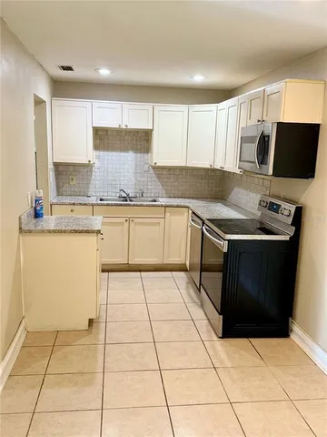 a kitchen with stainless steel appliances a sink a stove a microwave a counter top space and cabinets