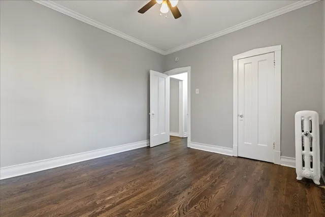 an empty room with wooden floor chandelier fan and windows