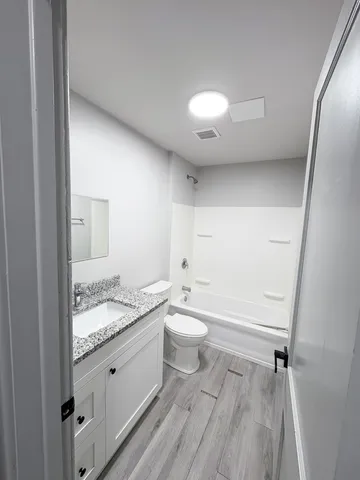 a bathroom with a granite countertop sink a toilet and shower