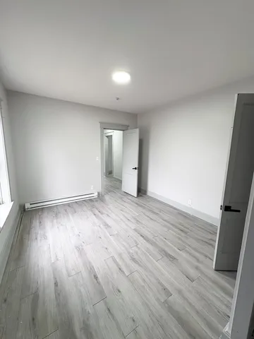 an empty room with wooden floor and window