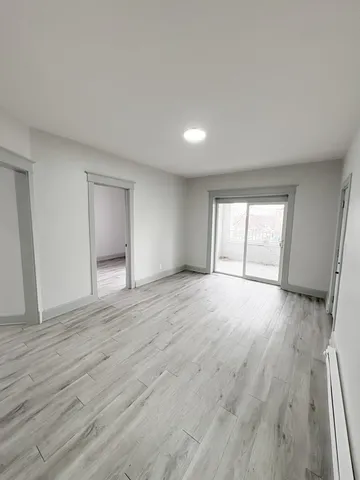 a view of an empty room with wooden floor and window