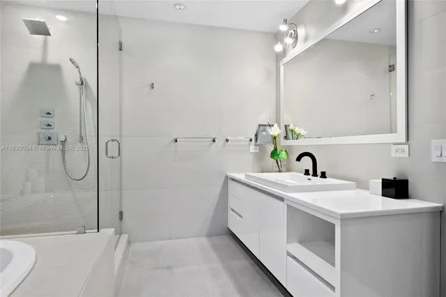 a bathroom with a sink and mirror with bathtub