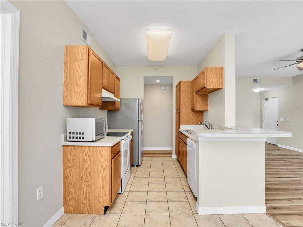 7935 Preserve Circle, Unit 423 Naples, FL 34119 - Photo 9 of 30 a kitchen with stainless steel appliances granite countertop a stove a sink and a refrigerator
