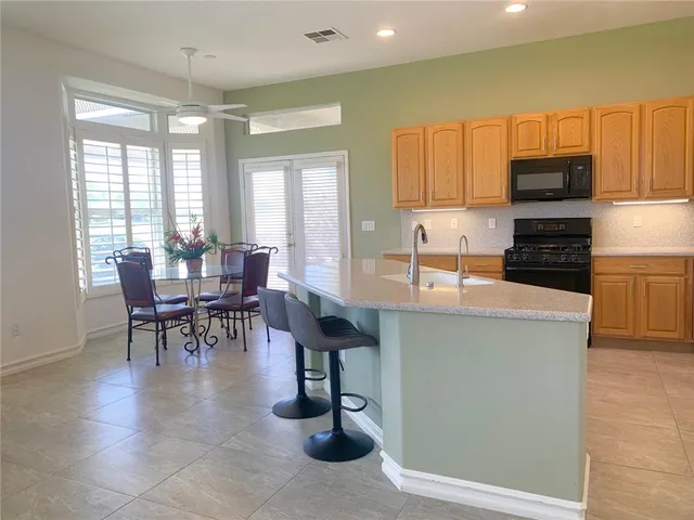 a kitchen with granite countertop a table chairs microwave and sink