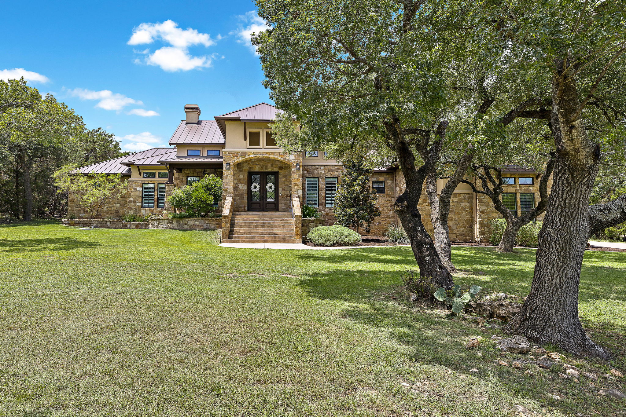 View of front facade featuring a standing seam roof, a metal roof, a chimney, a front yard, and stone siding
