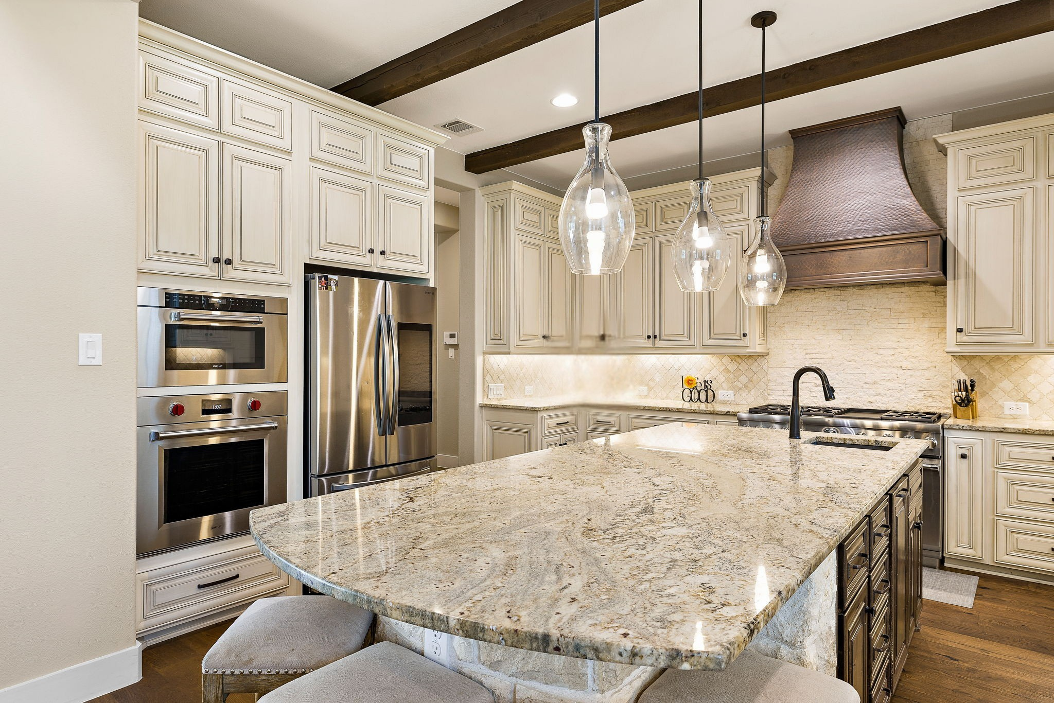 117 Covington Cove Georgetown, TX 78628 - Photo 13 of 40 Kitchen featuring cream cabinetry, light stone counters, a kitchen bar, stainless steel appliances, and dark wood-style floors