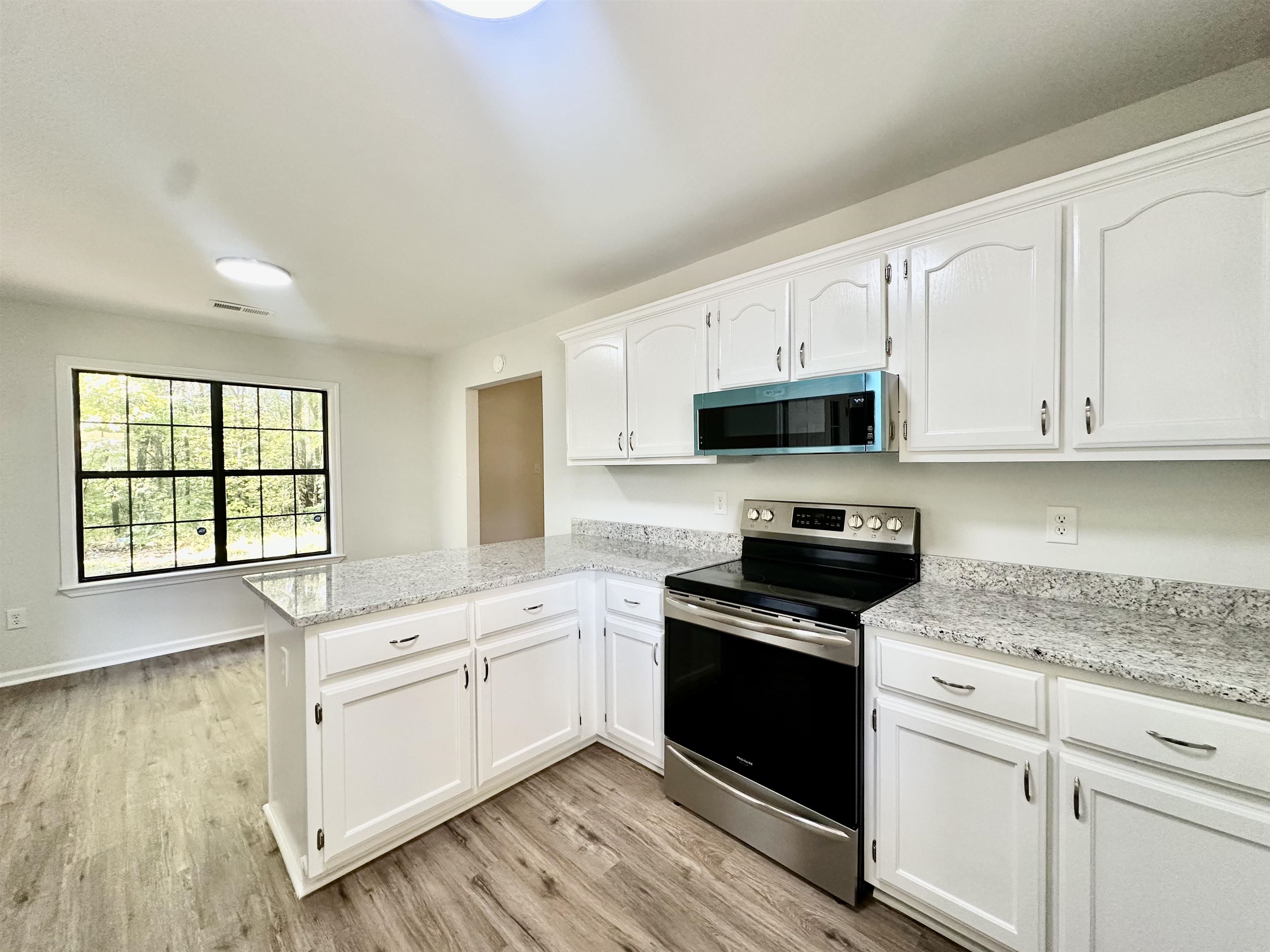 249 Mignon Road Atoka, TN 38004 - Photo 13 of 28 Kitchen featuring appliances with stainless steel finishes, white cabinets, a peninsula, and light wood finished floors