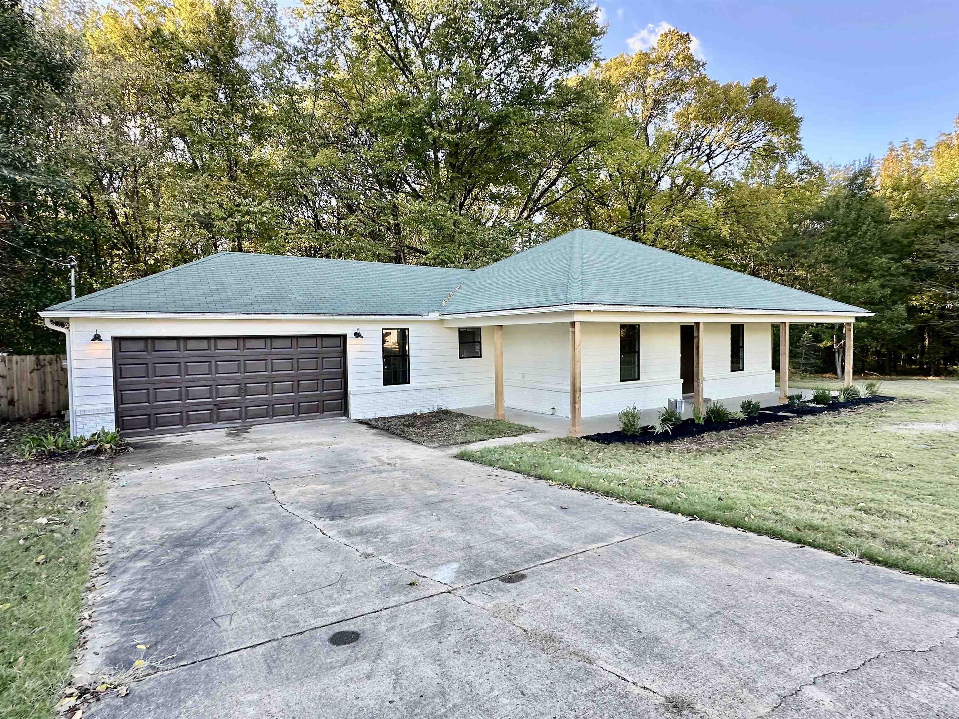 249 Mignon Road Atoka, TN 38004 - Photo 4 of 28 Ranch-style house featuring driveway, an attached garage, view of wooded area, a front yard, and a porch