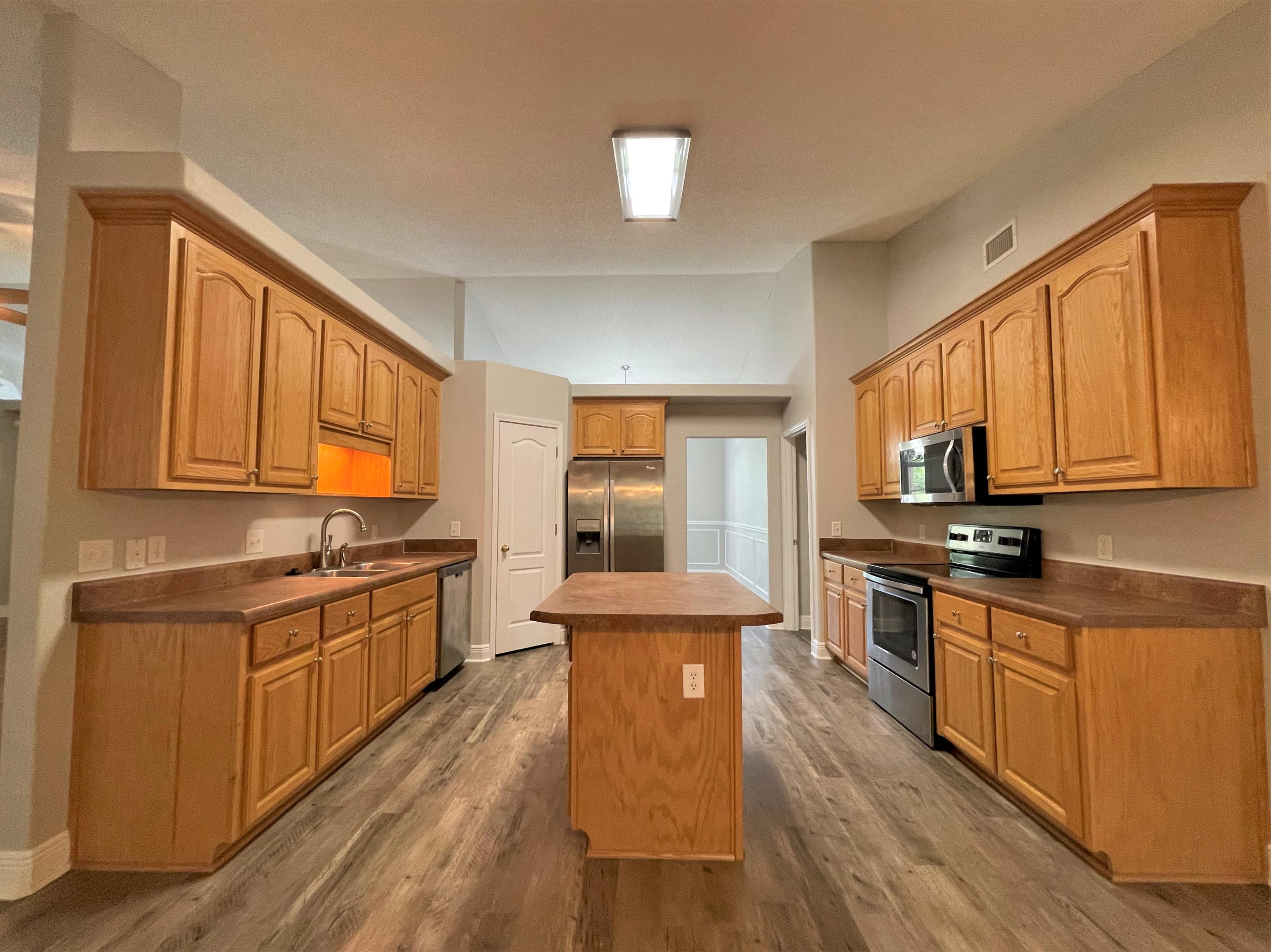 711 Fennec Fox Preserve Crestview, FL 32536 - Photo 8 of 33 a kitchen with stainless steel appliances granite countertop wooden cabinets a sink dishwasher a stove and a refrigerator with wooden floor