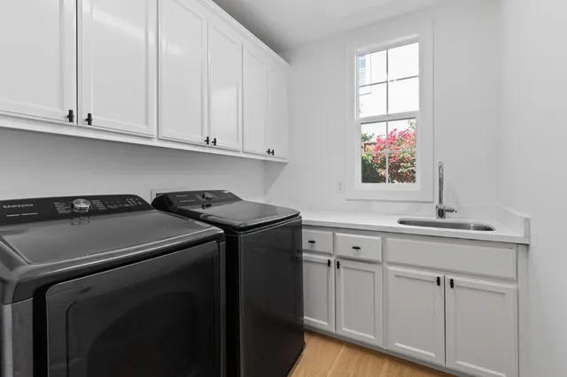 a utility room with stainless steel appliances white cabinets and a window