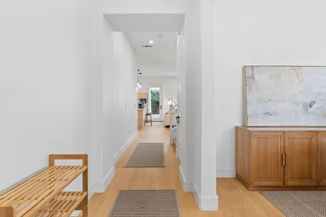 a view of a hallway with wooden floor and a bathroom