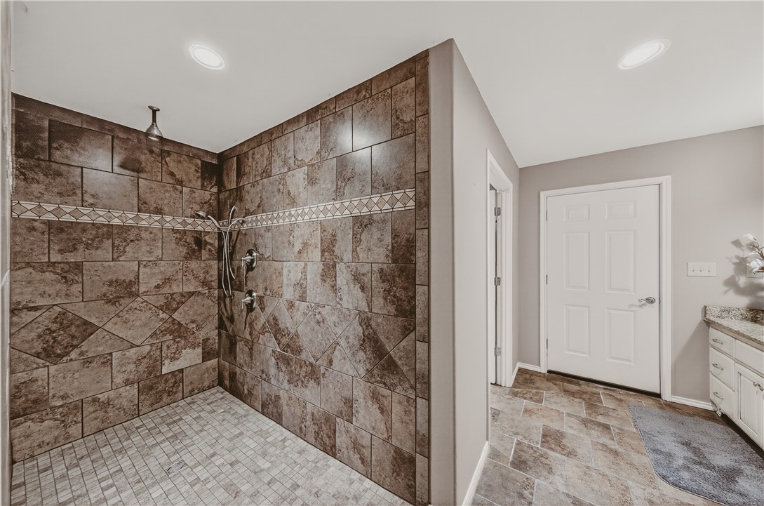 648 Dequeen Lake Road De Queen, AR 71832 - Photo 8 of 46 Primary shower featuring a spacious walk-in shower with stone tile walls, a rain showerhead, and a separate handheld shower fixture