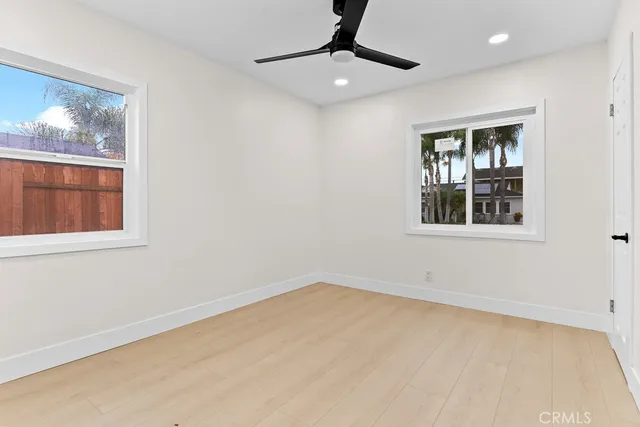 a view of an empty room with window and wooden floor