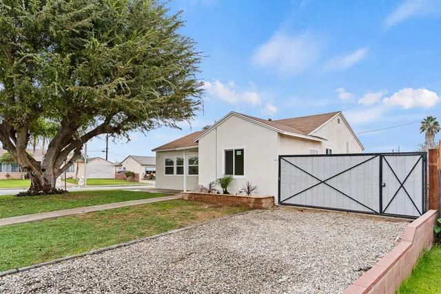 a view of a white house next to a yard with big trees