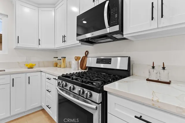 a kitchen with stainless steel appliances granite countertop white cabinets and a stove