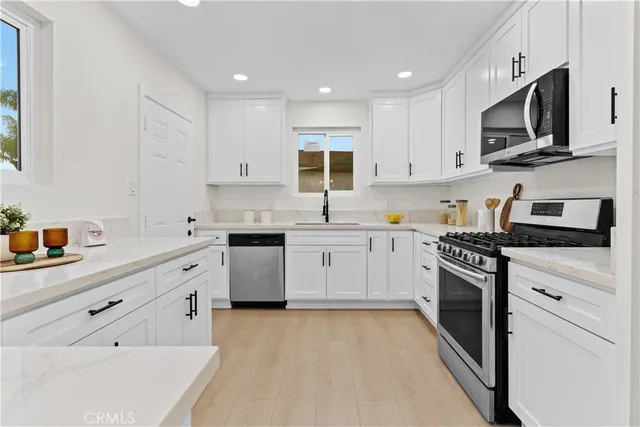 a kitchen with granite countertop white cabinets and stainless steel appliances