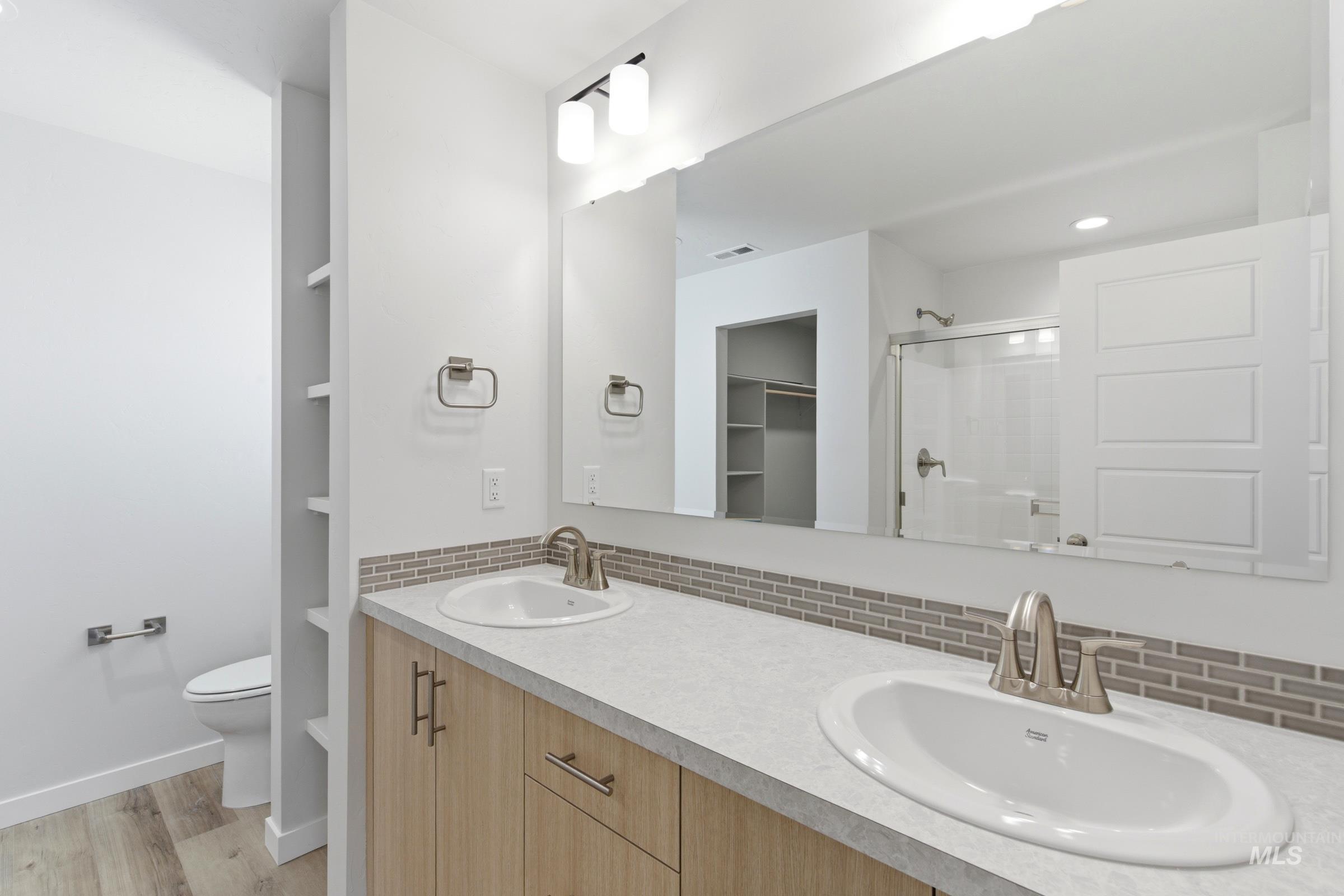 8317 South Tyrion Way Kuna, ID 83634 - Photo 21 of 22 Dual vanity with light wood-finish cabinetry, light grey countertop, and mosaic tile backsplash