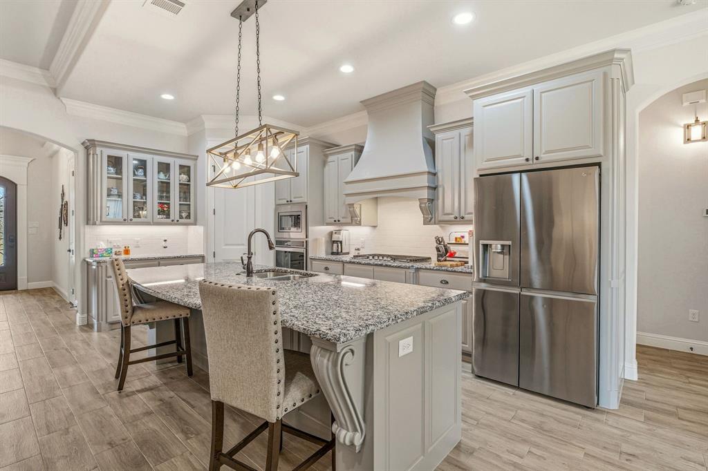 3024 Reed Court Granbury, TX 76048 - Photo 11 of 40 a kitchen with stainless steel appliances granite countertop a table chairs stove and refrigerator