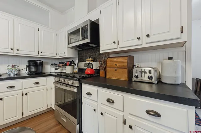 a kitchen with stainless steel appliances granite countertop white cabinets stove top oven and sink