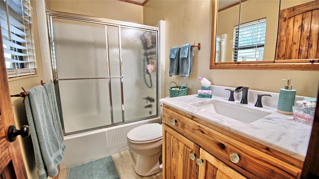 858 Ford Road Bowie, TX 76230 - Photo 7 of 40 a bathroom with a granite countertop sink toilet and shower
