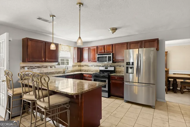 a kitchen with stainless steel appliances granite countertop a refrigerator a stove a sink and a microwave