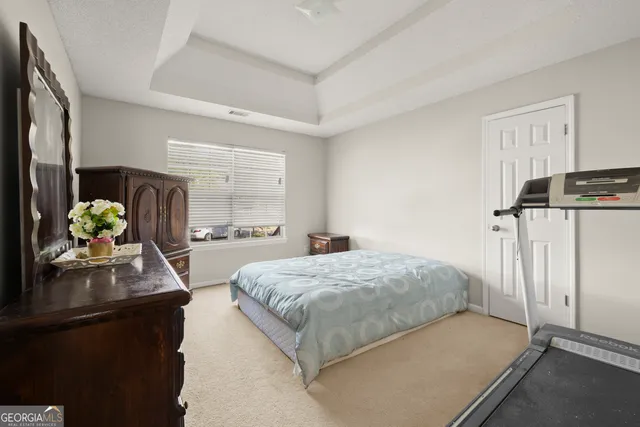 a bedroom with a bed dresser flowerpot and window