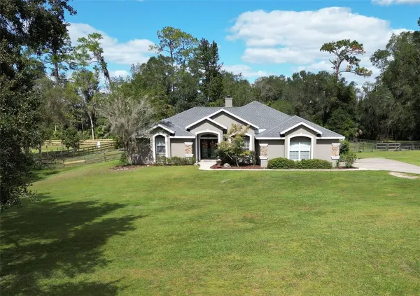 a front view of a house with a yard and trees