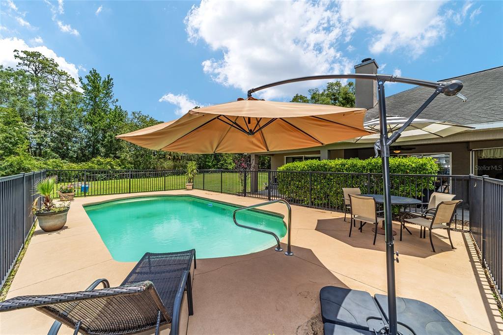 2151 Southeast 59th Street Ocala, FL 34480 - Photo 11 of 72 a view of a swimming pool with a table and chairs under an umbrella