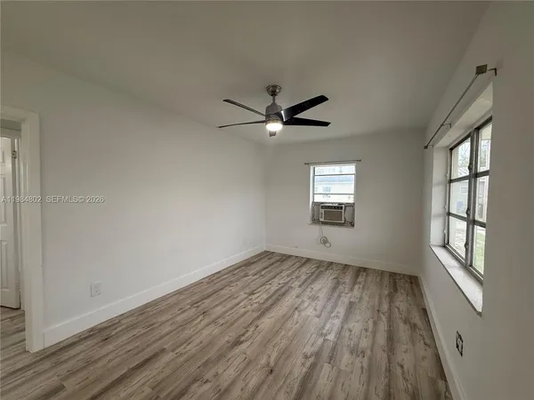 a view of an empty room with a window and wooden floor
