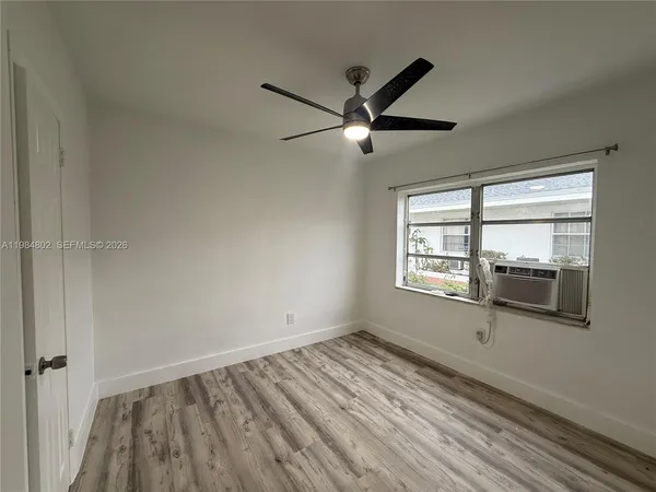a view of empty room with wooden floor and fan