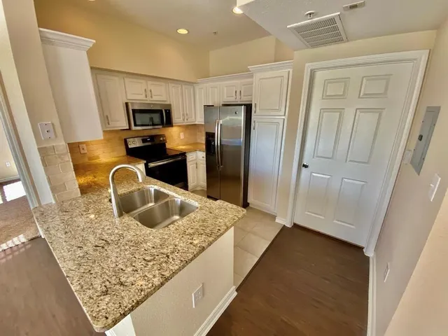 a kitchen with stainless steel appliances granite countertop a sink refrigerator and microwave