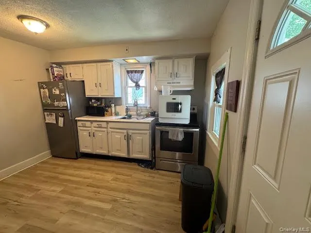 a kitchen with stainless steel appliances a sink cabinets and wooden floor