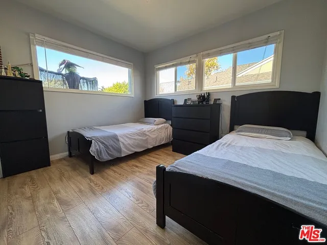 a bedroom with two beds and a dresser next to a window