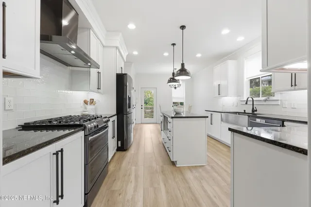 a kitchen with stainless steel appliances granite countertop a sink a stove and a wooden floor