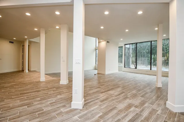 a view of an empty room with wooden floor and windows